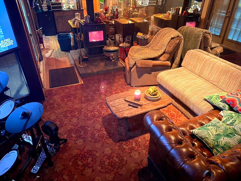 Wide view of the lounge at City Lights Recording Studio with wood stove and drum kit